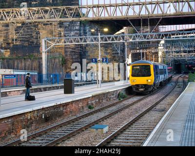 Un singolo pendolarismo attende su un binario alla stazione di Lime Street a Liverpool, Regno Unito, mentre arriva un treno per pendolarismo della Northern Rail. Foto Stock