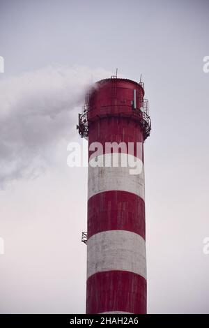 Fumante camino a strisce di una pianta o di una fabbrica su uno sfondo cielo Foto Stock