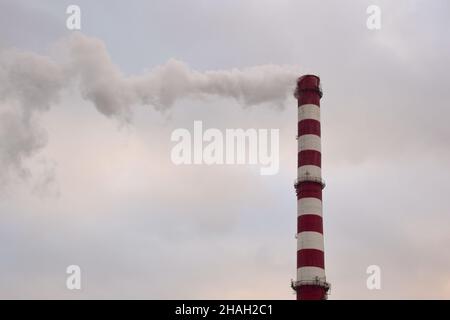 Fumante camino a strisce di una pianta o di una fabbrica su uno sfondo cielo Foto Stock