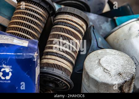 Cumulo di vecchi filtri olio usati oleosi in officina meccanica, pronti per il riciclaggio Foto Stock