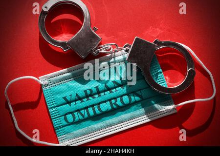 Manette appoggiate su una maschera facciale con il testo "Variant Omicron" Foto Stock