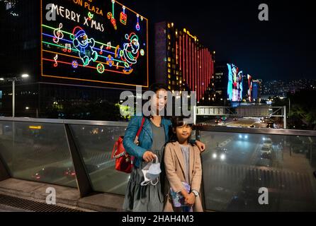 Hong Kong, Cina. 11th Dic 2021. HONG KONG, CINA - 11 DICEMBRE: Una madre e sua figlia scattano una foto con una decorazione leggera di Natale dietro di loro che copre un intero edificio a Hong Kong il 11 dicembre 2021. Hong Kong è in forte allerta la diffusione della variante Omicron durante le vacanze. (Foto di Miguel candela/SOPA Images/Sipa USA) Credit: Sipa USA/Alamy Live News Foto Stock