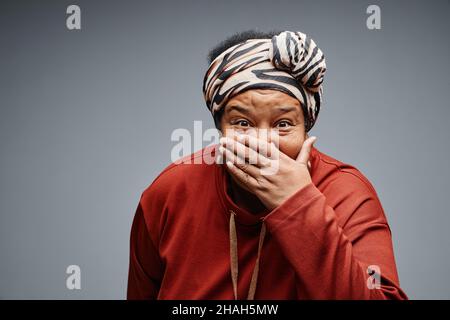 Vita in su ritratto di spensierata donna nera anziana facendo volti sorpresi su sfondo bianco, spazio copia Foto Stock