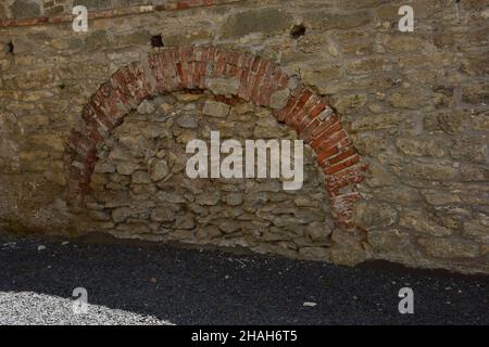 Nella parete di un antico edificio medievale in muratura si trova un ingresso ad arco alla prigione Foto Stock