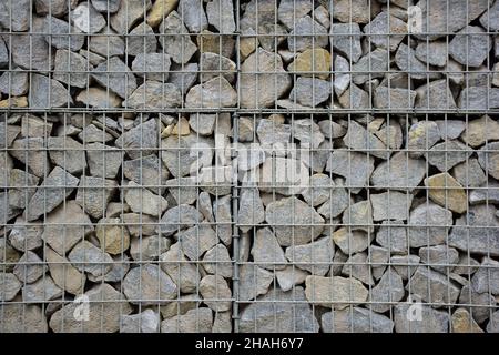 Una grande recinzione di molti ciottoli di pietra supportati da un traliccio di pietra per l'intero telaio. Il design occupa l'intero sfondo Foto Stock