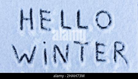 Ciao Winter parole scritte sulla superficie di un campo di neve. Inizio di nuova stagione o concetto di inverno. Messa a fuoco selettiva. Banner. Foto Stock