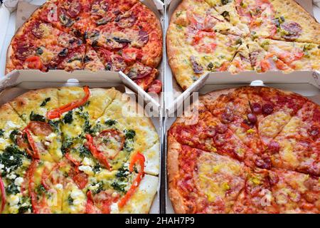 Quattro scatole di pizza di diversi tipi e ripieni si trovano l'una accanto all'altra Foto Stock