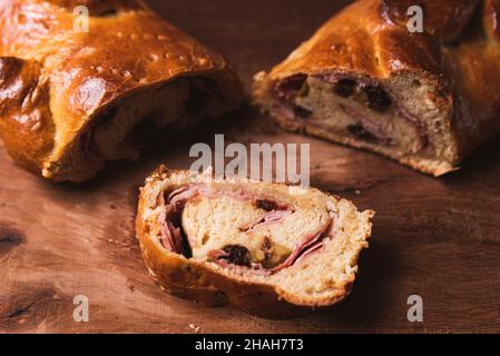 una fetta di cibo tradizionale venezuelano di natale conosciuto come 'pan de jamon' che significa prosciutto con pane con decorazioni natalizie su tavola di legno, con prosciutto, Foto Stock