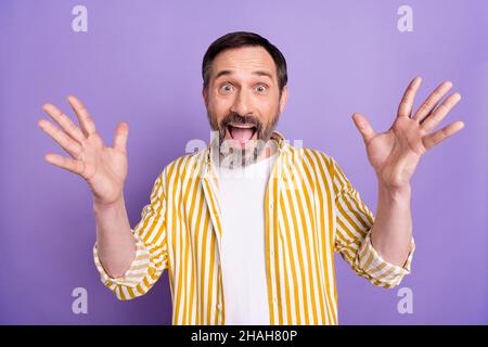 Foto di bello scioccato età ported gentleman indossare camicia gialla sorridente braccia sollevanti isolato viola sfondo di colore Foto Stock