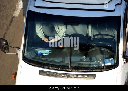 La cabina dell'auto viene fotografata dalla parte superiore del ponte da un'angolazione elevata. Un conducente e un passeggero viaggiano in auto Foto Stock