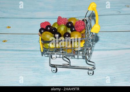 Lamponi, uva spina e ribes sono colti in un piccolo carrello giocattolo giallo. Primo piano fotografato Foto Stock