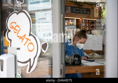 Stoccarda, Germania. 13th Dic 2021. Un dipendente di un centro di test Corona in una gelateria del centro si trova al banco della reception. Credit: Marijan Murat/dpa/Alamy Live News Foto Stock