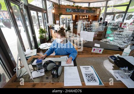 Stoccarda, Germania. 13th Dic 2021. Un dipendente di un centro di test Corona in una gelateria del centro si trova al banco della reception. Credit: Marijan Murat/dpa/Alamy Live News Foto Stock