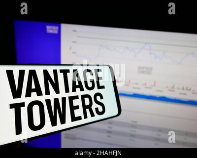 Telefono cellulare con logo della società tedesca di infrastrutture Vantage Towers AG sullo schermo di fronte al sito web aziendale. Mettere a fuoco sulla sinistra del display del telefono. Foto Stock