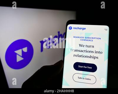 Persona che detiene smartphone con sito web della società statunitense di software in abbonamento Recharge Inc. Sullo schermo con logo. Concentrarsi sul centro del display del telefono. Foto Stock