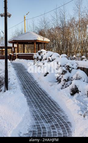 un sentiero sgomberato dopo una nevicata che porta ad un gazebo in legno. Foto di alta qualità Foto Stock