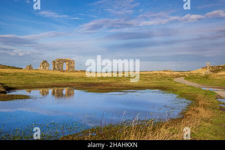 Le rovine della chiesa di St Dwynwen si riflettevano nell'acqua sull'isola di Llanddwyn, Isola di Anglesey, Galles del Nord Foto Stock