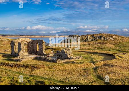 La croce celtica e le rovine della chiesa di San Dwynwen sull'isola di Llanddwyn, Isola di Anglesey, Galles del Nord Foto Stock