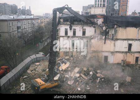 L'attrezzatura da costruzione distrugge una casa sul sito. Smantellamento e demolizione di un edificio in città. Il relitto di una vecchia casa abbandonata. CLE Foto Stock