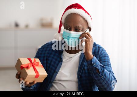 Senior African Man parlare al telefono ordinare regali consegna indoor Foto Stock