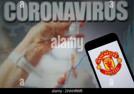 Foto del file datata 09-01-2021 del logo del Manchester United Football Club visto su un telefono cellulare con un'illustrazione di Coronavirus su un monitor sullo sfondo. Il Manchester United è in trattativa con la Premier League per sapere se la partita di domani a Brentford dovrebbe Passi pure e ha chiuso le operazioni di prima squadra alla loro base di addestramento di Carrington per 24 ore per minimizzare il rischio di ulteriori infezioni di Covid-19, il club ha annunciato. Data di emissione: Lunedì 13 dicembre 2021. Foto Stock