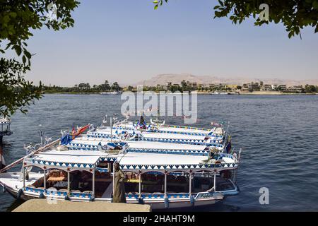 Fila di barche decorate per escursioni sul Nilo, ormeggiata al molo in attesa di turisti. Vacanza, tempo libero e avventura viaggi. Luxor, Egitto - Ottobre Foto Stock
