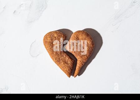 Biscotto a forma di cuore rotto su sfondo di marmo bianco. Concetto di San Valentino. Foto Stock