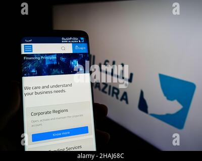 Persona che detiene il cellulare con il sito web della compagnia Saudita Bank Aljazira (BAJ) sullo schermo di fronte al logo. Concentrarsi sul centro del display del telefono. Foto Stock