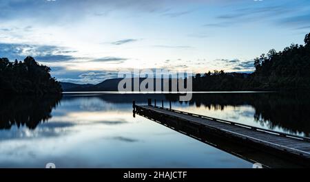 Calma Lago Mapourika Franz in Nuova Zelanda con il riflesso degli alberi e bacino sulla superficie Foto Stock