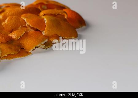 Sfondo arancione. Sfocatura sfondo Natale sfocato dalle bucce di arancio e mandarino su sfondo bianco. Molti piccoli pezzi di buccia secca. Foto Stock