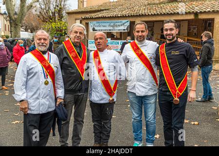 Cinque uomini che indossano le fasce rosse e le medaglie di una confraternita gastronomica si trovano davanti alla sala del mercato all'apertura della stagione del mercato dei tartufi di Aups, dipartimento di Var, Francia; il presidente del sindacato Philippe De Santis apre tradizionalmente il mercato il primo giovedì di dicembre. Foto Stock