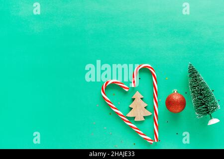 Caramelle natalizie a forma di cuore con decorazioni su sfondo verde. Appartamento vacanza minimalista con spazio per la copia del testo. Foto Stock