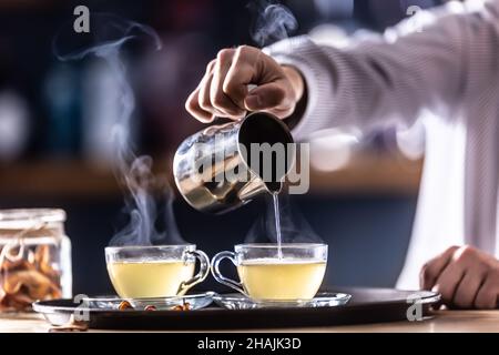 Il barista versa il VIN brulé caldo o una bevanda invernale a base di whiskey Teddy caldo. Foto Stock