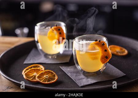 Bevanda CALDA TODDY a base di whiskey, sciroppo semplice, acqua calda, chiodi di garofano e scorza d'arancia pronti per i clienti nel pub al banco del bar. Foto Stock