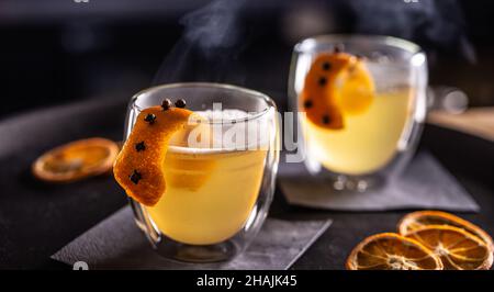 Bevanda CALDA TODDY a base di whiskey, sciroppo semplice, acqua calda, chiodi di garofano e scorza d'arancia pronti per i clienti nel pub al banco del bar. Foto Stock