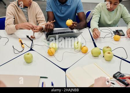 Scatto corto di insegnante afro-americano che lavora sugli esperimenti di scienza con il gruppo vario dei bambini Foto Stock