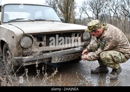 Mayorske, Donetsk, Ucraina. 11th Dic 2021. Il soldato ucraino dell'esercito ha visto fissare la sua piastra dell'automobile sulla strada in Mayorske.il villaggio di Mayorske è situato appena vicino al checkpoint Ucraina-controllato nella regione di Donetsk sulla linea anteriore. Il lavoro del checkpoint 'Mayorske' ancora sospeso. Tensioni elevate quando le forze militari russe si riuniscono vicino al confine con l’Ucraina. (Credit Image: © Andriy Andriyenko/SOPA Images via ZUMA Press Wire) Foto Stock