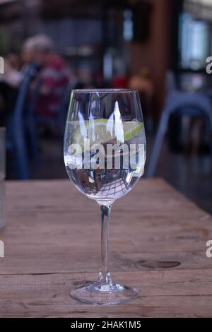 Bicchiere di acqua frizzante con limone e ghiaccio su un tavolo di legno Foto Stock