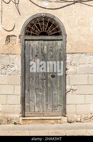 Antica porta in legno della tipica antica casa in pietra mediterranea in Sicilia. Foto Stock