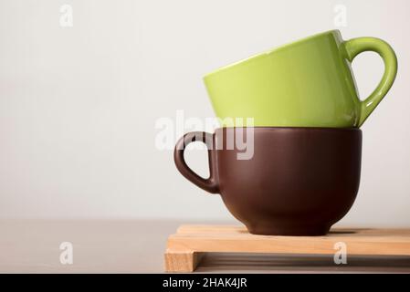due tazze di caffè o tè marrone e verde su legno con sfondo bianco Foto Stock