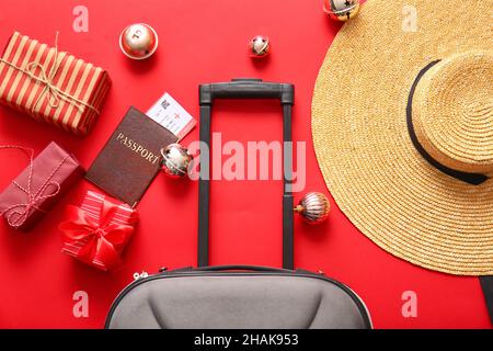 Composizione con valigia, scatole regalo, cappello e documenti su sfondo colorato, primo piano. Vacanza di Natale concetto Foto Stock