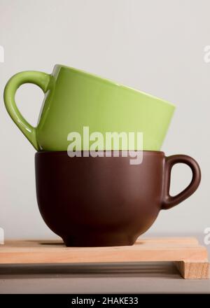 due tazze di caffè o tè marrone e verde su legno con sfondo bianco Foto Stock