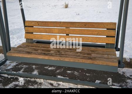 In una giornata invernale nevosa, le altalene nella strada della città si avvicinano. Foto Stock