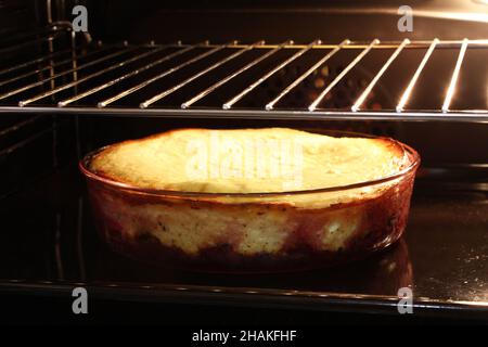 Casseruola di formaggio casolare con lamponi e nocciole in forma di vetro è cotto nel forno. Primo piano. Foto Stock