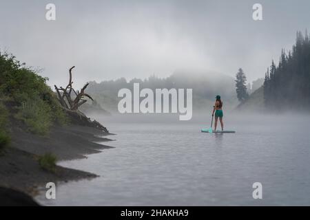 7/14/21 - Crested Butte, Colorado - una donna dimostra come fare i cavalletti e lo yoga su una tavola da pagaia. Foto Stock