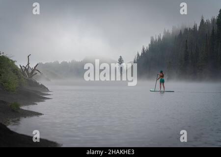 7/14/21 - Crested Butte, Colorado - una donna dimostra come fare i cavalletti e lo yoga su una tavola da pagaia. Foto Stock