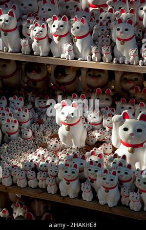 Statue tradizionali di gatto ondeggianti, conosciute anche come maneki-neko, al tempio di Gotokuji a Tokyo, in Giappone. Foto Stock