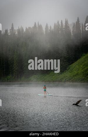 7/14/21 - Crested Butte, Colorado - una donna dimostra come fare i cavalletti e lo yoga su una tavola da pagaia. Foto Stock