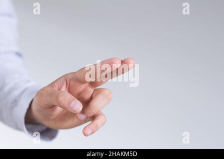 Mano maschile che punta a qualcosa contro uno sfondo bianco Foto Stock