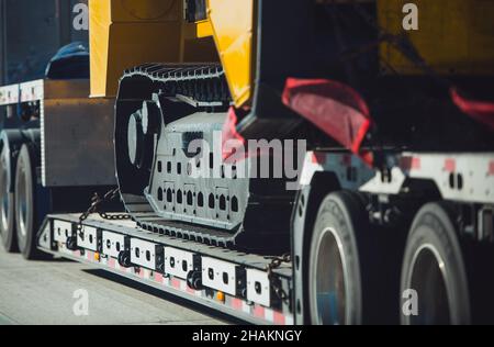 Trasporto di macchinari da costruzione per impieghi pesanti Long Haul su un semirimorco. Consegna dell'escavatore. Foto Stock